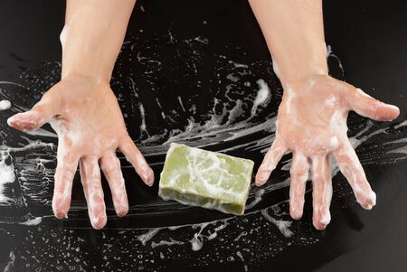 process of washing hands with blue soap, parts of the body in white foam on a black background, top...
