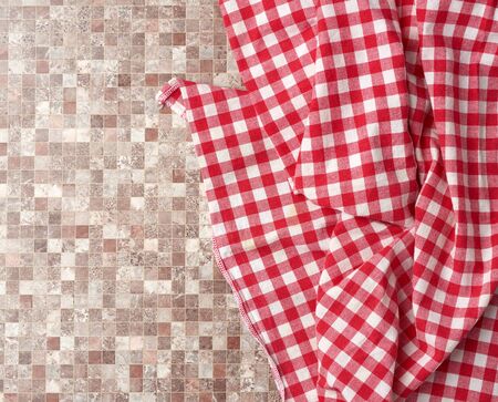 red checked cotton kitchen towel on a brown kitchen surface, top view, copy spaceの写真素材