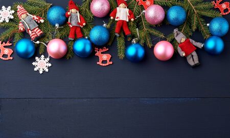 green spruce branches, Christmas blue and pink balls, carved wooden decor on a blue wooden background from boards, copy spaceの写真素材