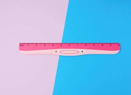 pink plastic ruler on a colored background, top view, flat layの写真素材
