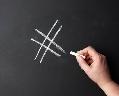 hand with chalk painted a hashtag on a black chalk board, close upの写真素材
