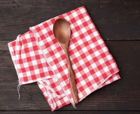 wooden spoon and red textile kitchen towel on brown wooden background, top viewの写真素材
