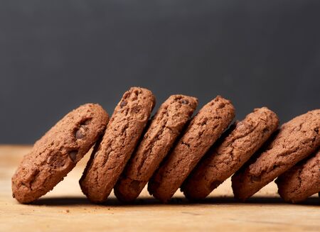 stack of baked round chocolate chip cookies on a brown wooden table, close upの写真素材