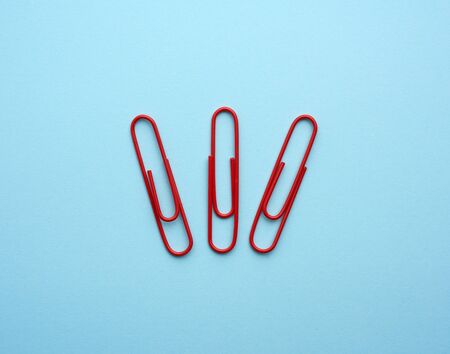 three metal red paper clips on a blue background, top view, close upの写真素材