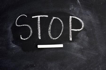 inscription english stop with white chalk on a black blackboard, concept of the end of the processの写真素材