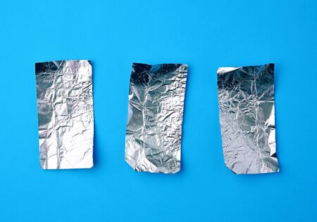 various crumpled foil used candy wrappers on a blue background, top viewの写真素材
