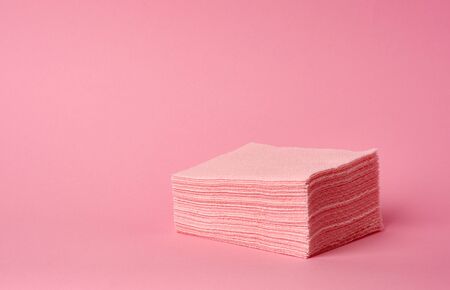 stack of paper disposable pink folded square napkins on a pink background, a place for inscriptionの写真素材