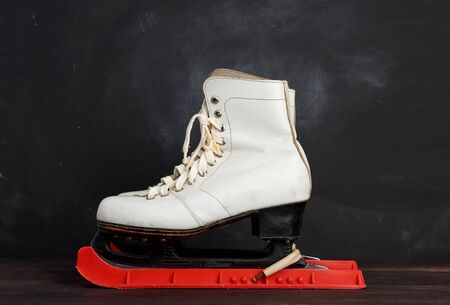 white leather skates for figure skating stand on a brown wooden background, sports equipmentの写真素材