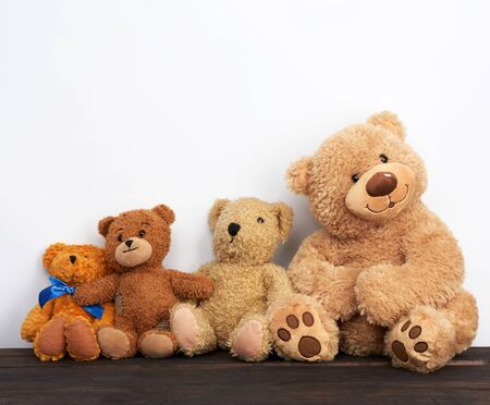 various brown teddy bears are sitting on a brown wooden table, white background, friendship conceptの写真素材