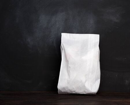 full white paper disposable bag on a wooden background, concept of rejection of plastic packaging, template for designer, packaging for contactless product delivery, copy spaceの写真素材
