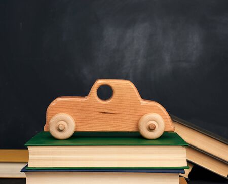 stack of books and wooden toy car on wheels, background from black chalk board, back to schoolの写真素材