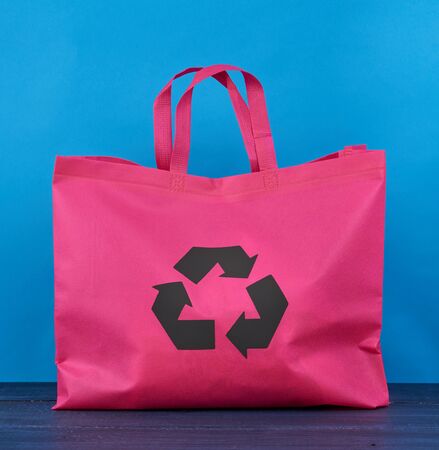 Full reusable pink viscose bag on blue wooden background, plastic waste reduction conceptの写真素材