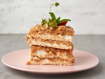 square pieces of meringue cake with cream on a pink plate , close upの写真素材