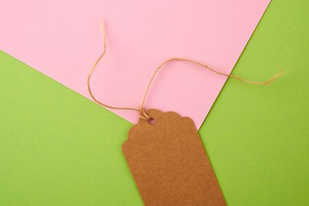 brown paper rectangular tag on a rope on a colored background, flat lay