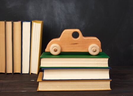 stack of books and wooden toy car on wheels, background from black chalk board, back to schoolの写真素材
