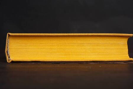 book in yellow hardcover against a black chalk board, close upの写真素材