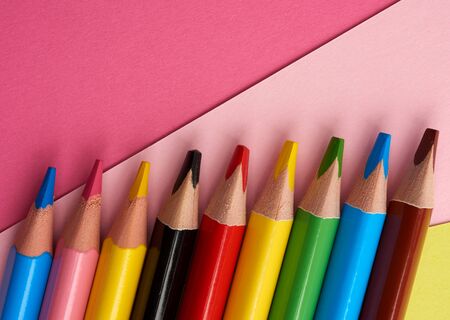 sharpened colored wooden pencils on an abstract pink background of cardboard, top view, place for an inscriptionの写真素材