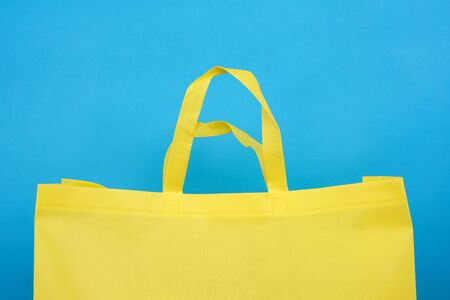 reusable yellow viscose bag on blue background, plastic waste reduction concept