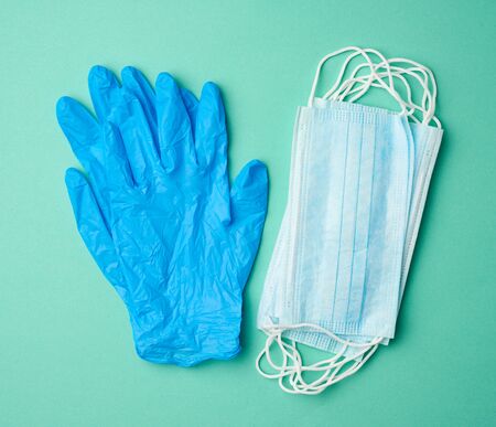 blue latex gloves and disposable masks on a green background, hygiene and virus protection...