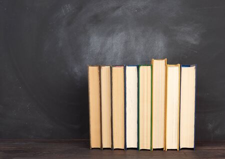 various hardback books on the background of an empty black chalk board, place for text, back to schoolの写真素材