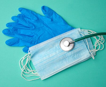 blue latex gloves and disposable masks on a green background, hygiene and virus protection accessories for epidemics and pandemics, overhead viewの写真素材