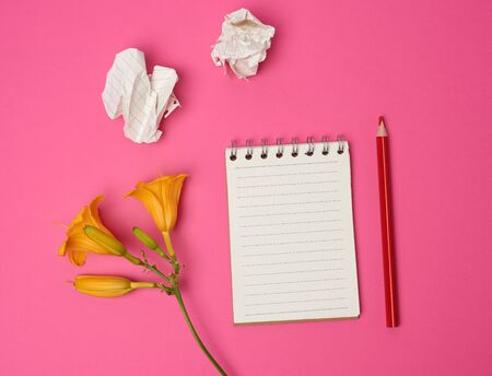 open notebook with white sheets and yellow flower on a pink background, flat lay