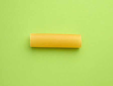 raw cannelloni pasta on a green background, top view