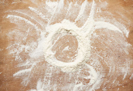 white wheat flour scattered on a brown wooden table, top view, funnel for liquid ingredientsの写真素材