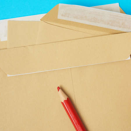 brown paper envelope and red wooden pencil on a blue background, top viewの写真素材