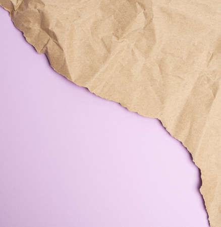 crumpled sheet of brown wrapping paper on a purple background, backdrop for the designer, copy spaceの写真素材