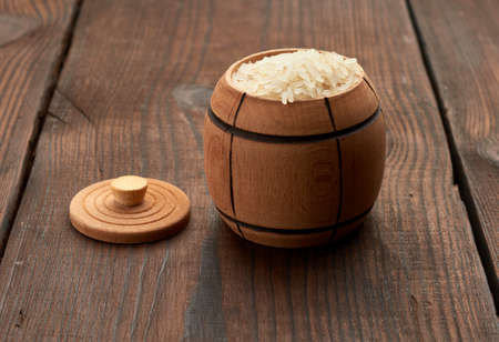 white raw rice in a wooden barrel with a lid on the table, close up