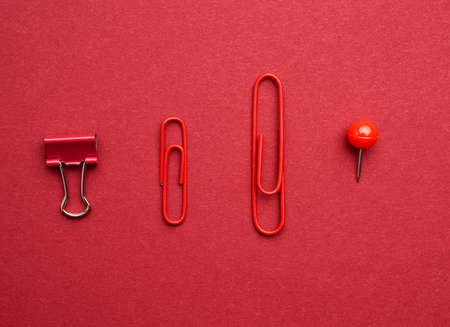 red metal paper clips, button on a red background, top viewの写真素材