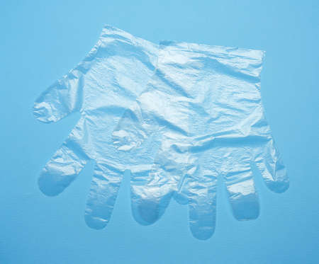 pair of disposable polyethylene gloves on a blue background, top view, flat layの写真素材