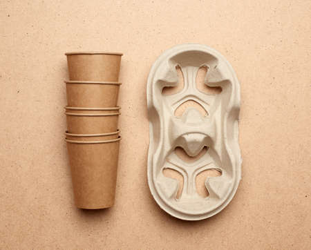 disposable brown paper craft cups and recycled paper holders on a brown wooden background, top view. plastic rejection concept and eco-friendly, zero wasteの写真素材