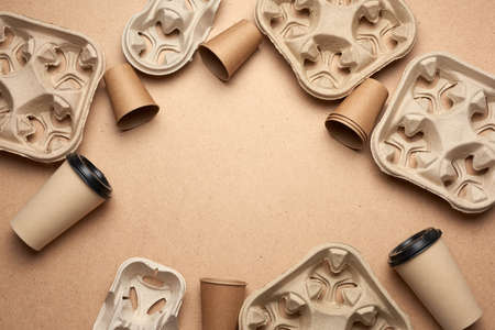 disposable paper cups from brown craft paper and recycled paper holders on a brown wooden background, top view, place for inscription. plastic rejection concept, zero wasteの写真素材