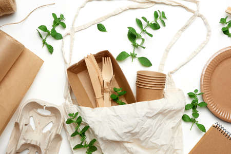 textile bag and disposable tableware from brown craft paper, green mint leaves on a whitebackground. View from above, plastic rejection concept, zero wasteの写真素材