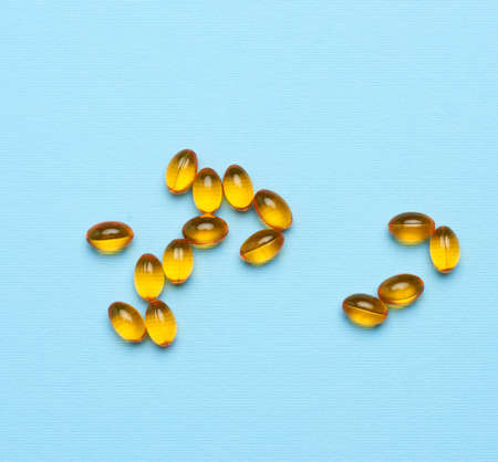 fish oil in oval yellow capsules on a blue background, top viewの写真素材