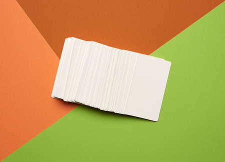 piles of white paper blank business cards on orange-green background, flat lay