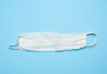 reusable mask of white cotton gauze on a blue background, homemade remedy for viral diseases, top...