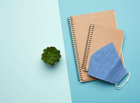 paper notebook and blue reusable mask on a blue background, homemade remedy for viral diseases, top...