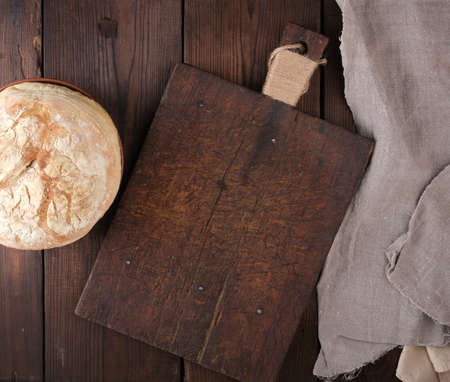baked round white wheat bread on a wooden old table, top view. Homemade food.