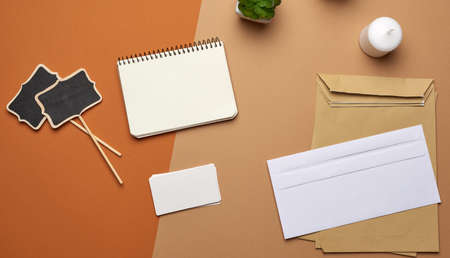 brown paper envelope and empty notebook on a brown background, top view