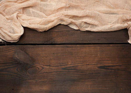 gray kitchen textile towel folded on a brown wooden table from old boards, top view, empty space. Rustic texture. Retro backgroundの写真素材