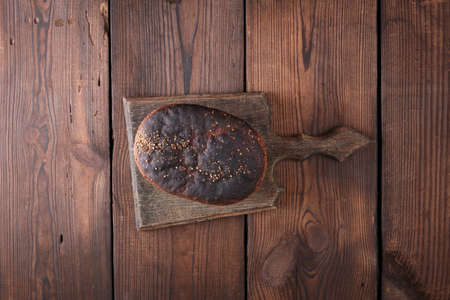 baked rye bread lies flour on a wooden old table, brown background, top viewの写真素材