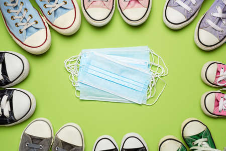 many multi-colored textile well-worn sneakers of different sizes and a stack of medical disposable...