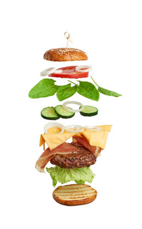 levitating cheeseburger ingredients: juicy meat cutlet, cheddar cheese, sesame bun, lettuce, white onion rings, slice of tomato, cucumber. Fast food isolated on white backgroundの写真素材