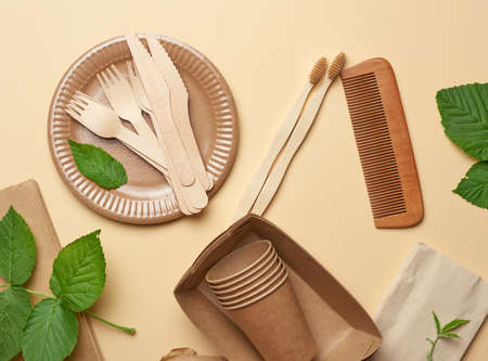 paper plates and cups from brown craft paper and wooden forks and knive on a beige background. Plastic rejection concept, zero wasteの写真素材