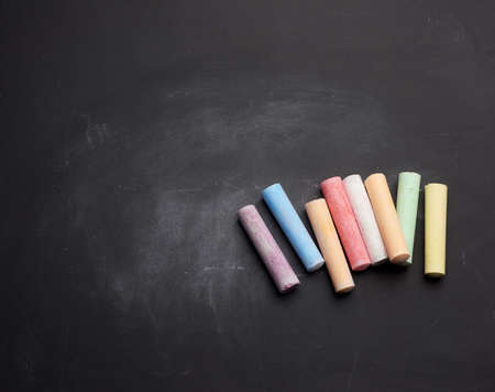 multicolored chalk on lie on empty black chalk board, place for inscriptionの写真素材