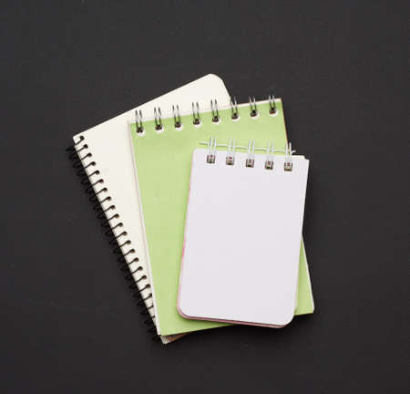 stack of spiral open notebooks with blank white sheets on a black background, top viewの写真素材