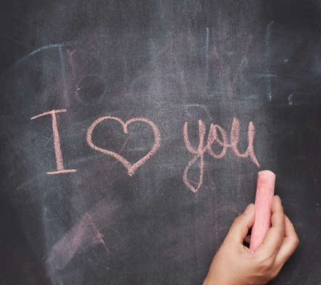 lettering in red chalk I love you on a black chalk board, close up